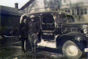 Vanha kuva, jossa kaksi miestä ja auto